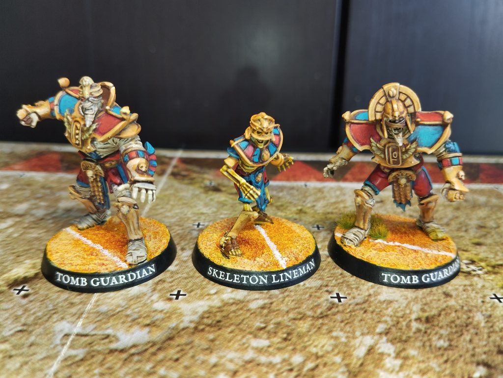 blood-bowl-gardien-des-tombes-squelettes-momies Équipe de Blood Bowl : figurines de Rois des Tombes Khemri peintes : gardiens et squelettes lineman avec socles terrain - Peinture Fox Squadron